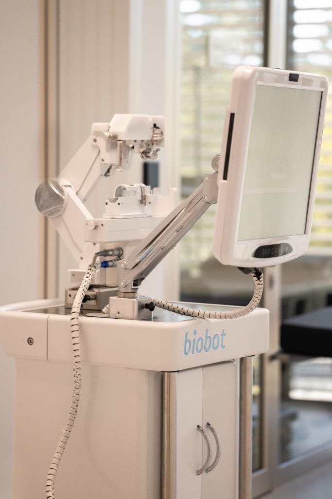 A medical robot labeled “biobot,” with a mechanical arm and screen, situated in a hospital environment.