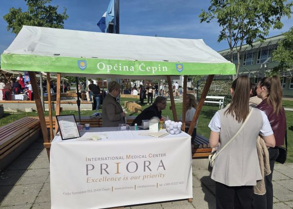Štand IMC Priora s natpisom “Excellence is our priority” na sajmu u Općini Čepin, djelatnici razgovaraju s posjetiteljima.