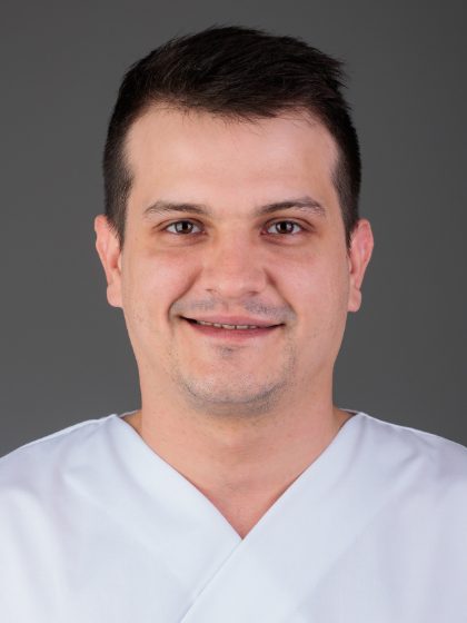 Muškarac u bijeloj odjeći na tamnoj pozadini, s kratkom tamnom kosom i blagim osmijehom na licu.