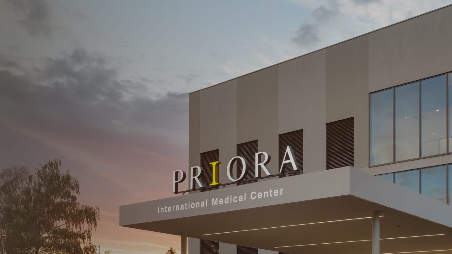 Zgrada međunarodnog medicinskog centra Priora, s jasnim natpisom na ulazu, u sumračnom nebu.