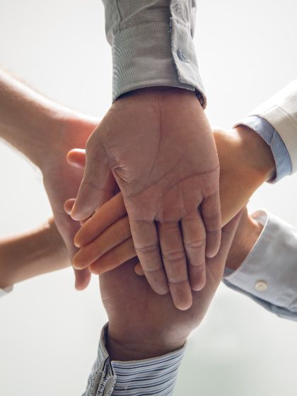 Skupina ruku koja položi jednu na drugu, simbolizirajući timski rad i suradnju.