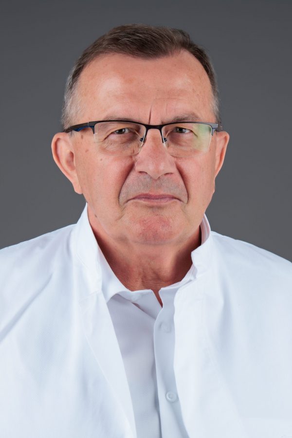 Muškarac u bijeloj košulji i naočalama, na neutralnoj pozadini.