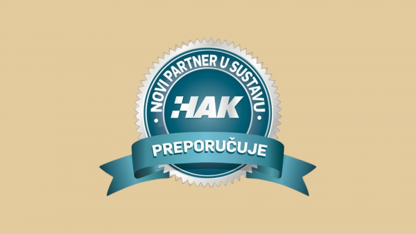 Teal and silver circular badge with a serrated edge, featuring the HAK logo and Croatian text “Novi partner u sustavu” with “Preporučuje” on a ribbon.