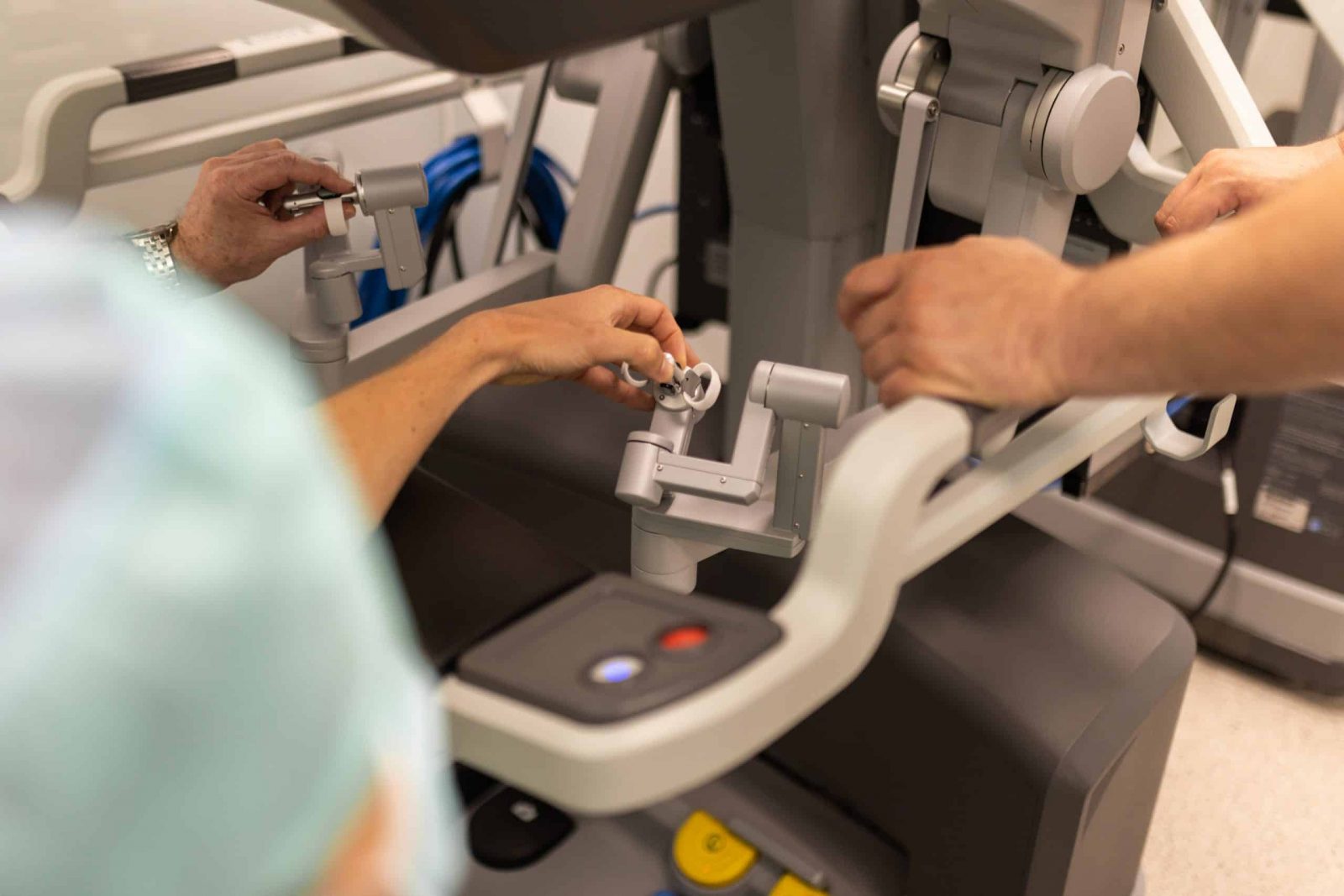 Osobe rukama upravljaju robotskim kirurškim sustavom u medicinskom okruženju.