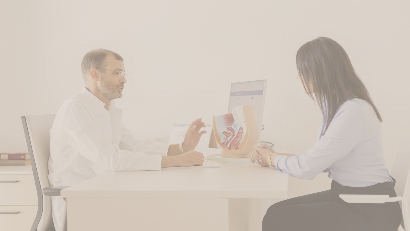 Liječnik u ordinaciji objašnjava pacijentu pomoću anatomskog modela zdjelice i ženskog reproduktivnog sustava tijekom konzultacije za stolom.